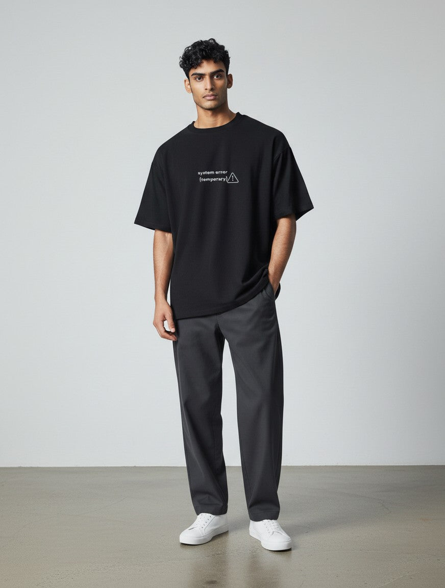 A man wearing a black mi-DONE oversized cotton t-shirt with a white system error graphic on the chest.