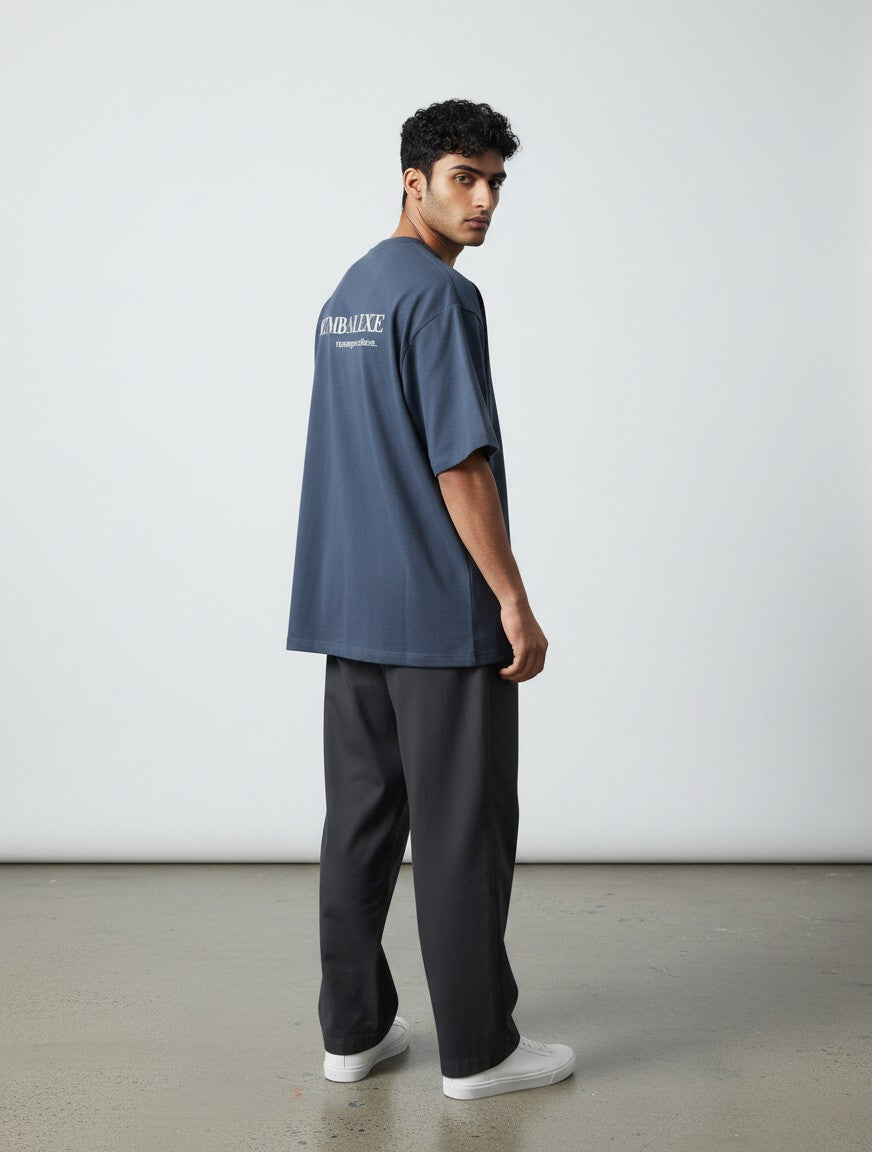 A man wearing a blue mi-DONE oversized cotton t-shirt with drop shoulders and white text on the back