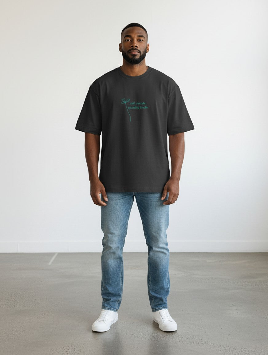 mi-DONE oversized charcoal grey cotton t-shirt with a small teal graphic print, worn by a man with blue jeans