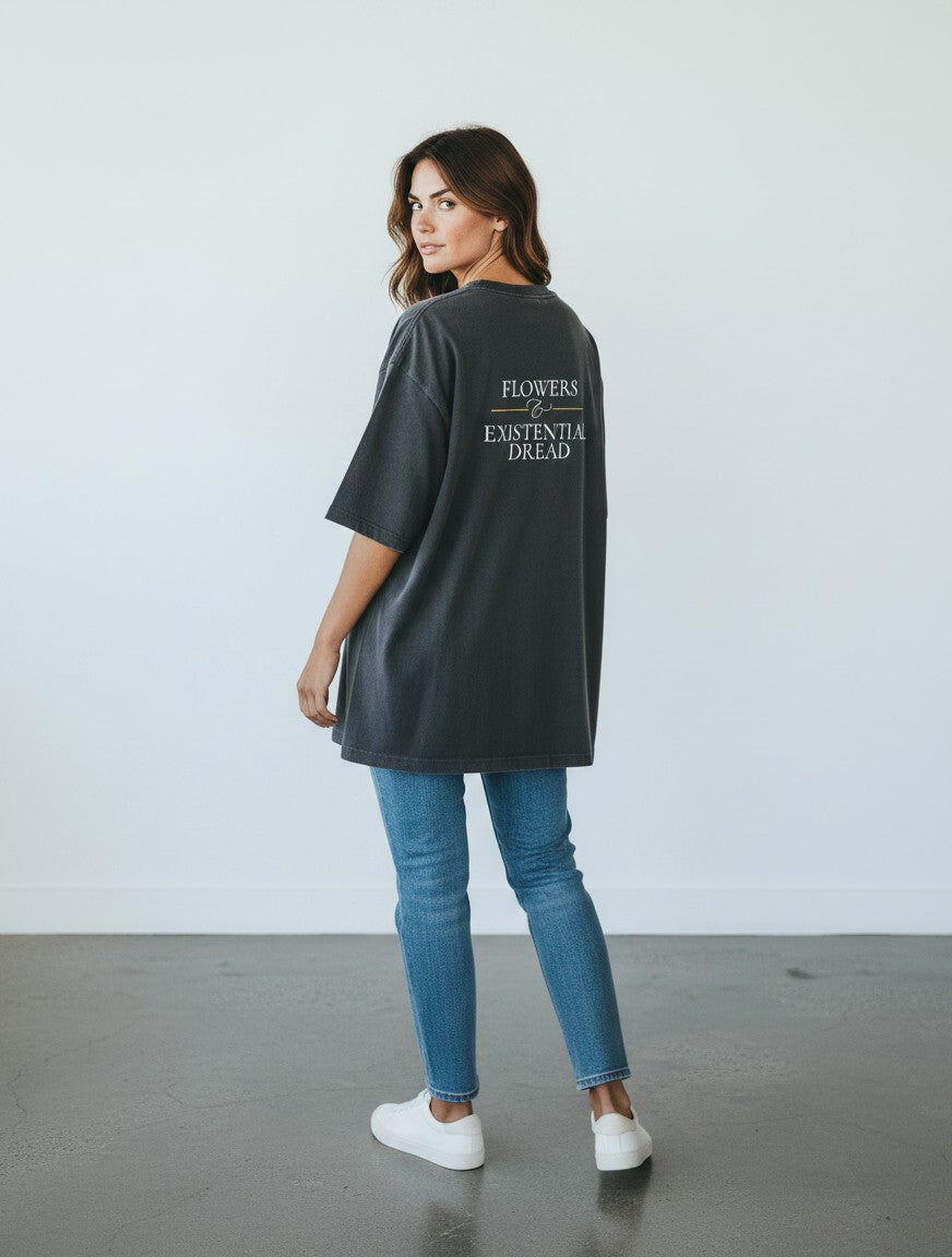 A woman wearing a charcoal oversized mi-DONE cotton t-shirt with Flowers & Existential Dread text on the back.