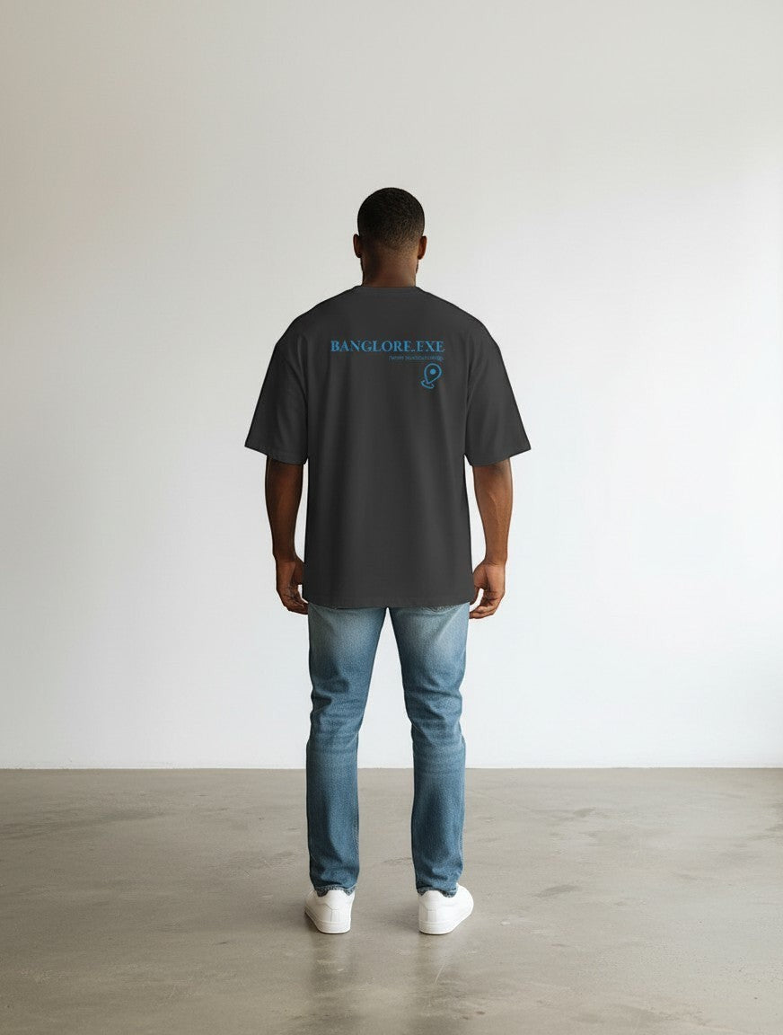 mi-DONE oversized charcoal grey cotton t-shirt with Currently Buffering back print, worn by a man with blue jeans.