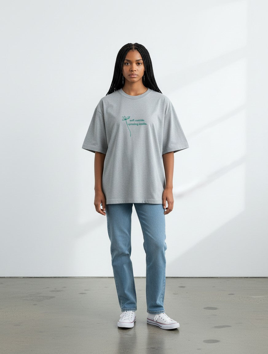Model wearing a grey mi-DONE oversized cotton t-shirt with a small green graphic print on the chest