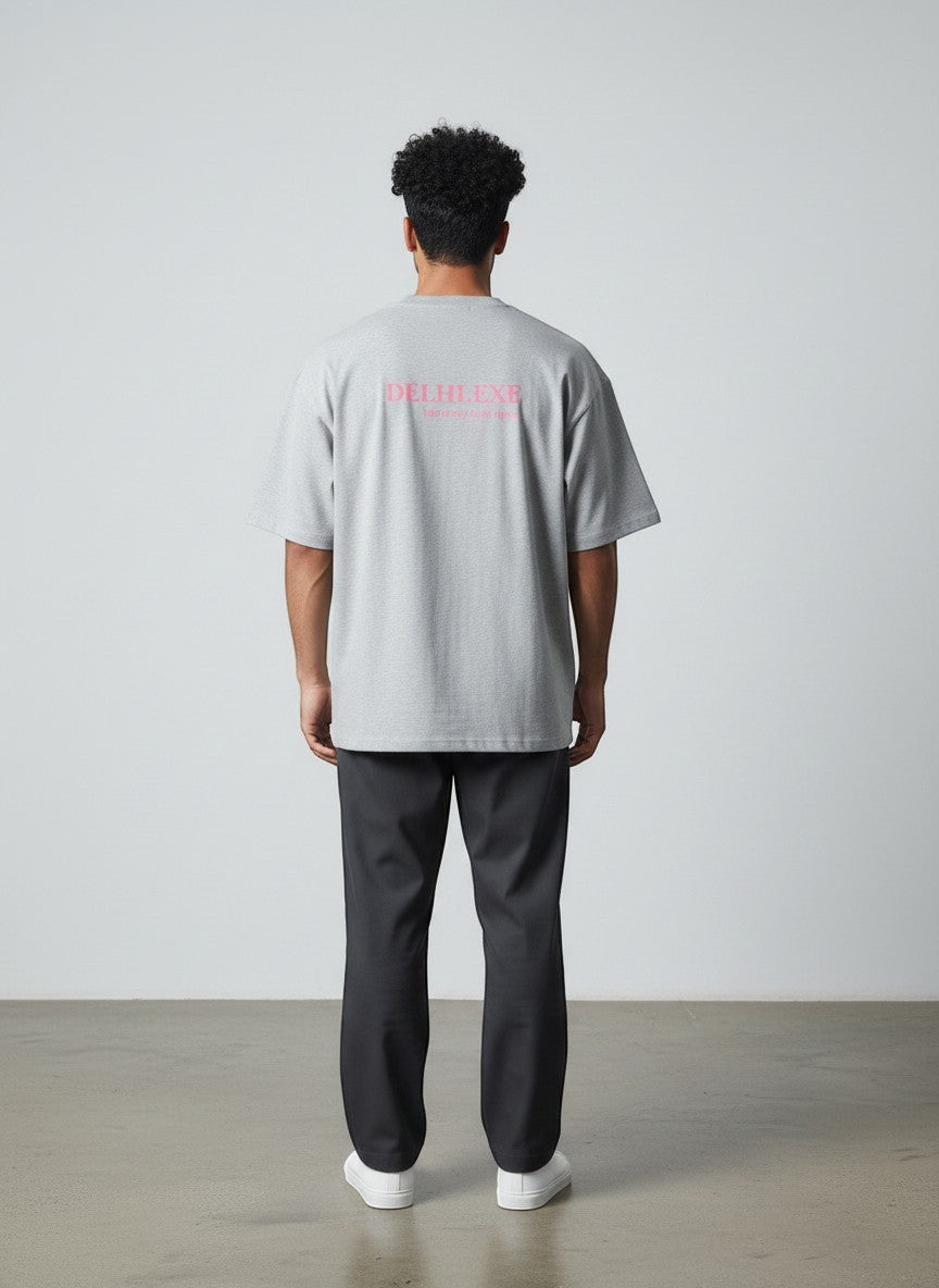 Back view of a man wearing a grey mi-DONE oversized cotton t-shirt with pink Delhi graphic print and drop shoulders.