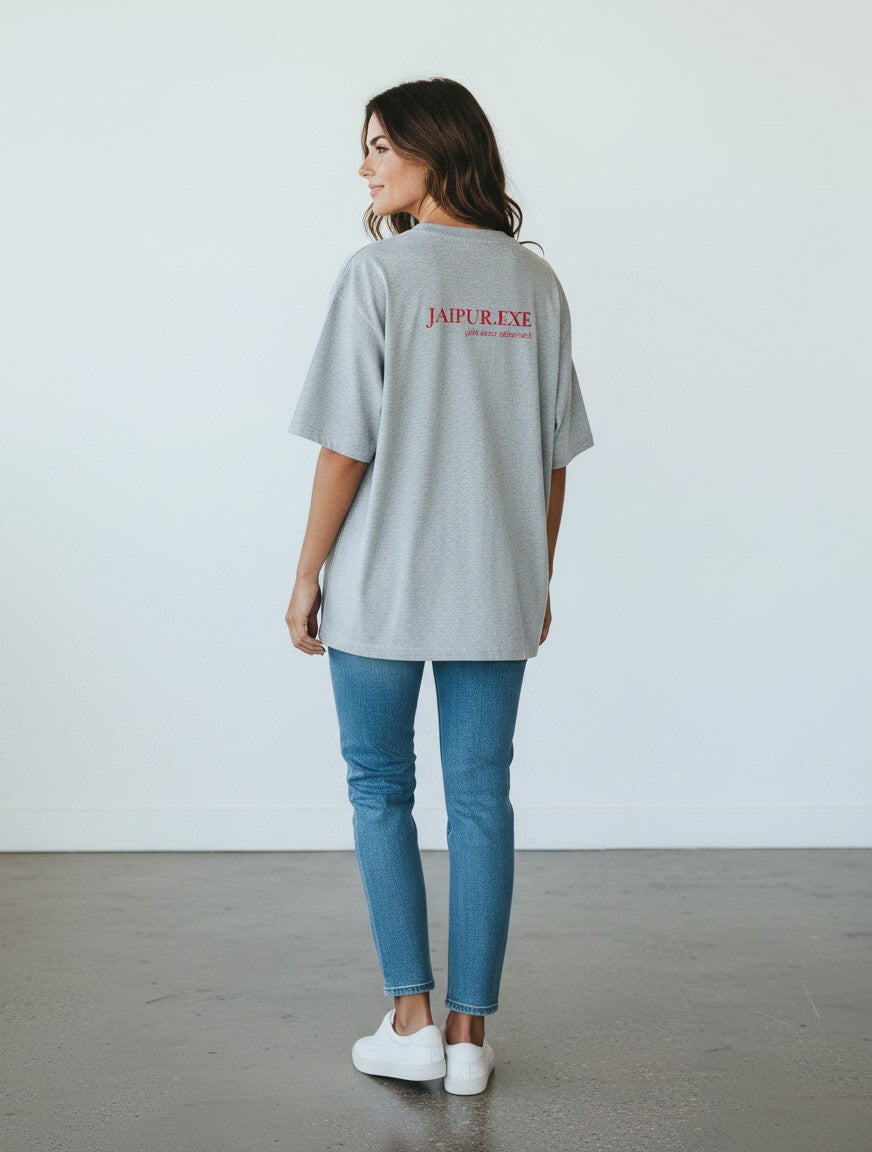 mi-DONE grey oversized cotton t-shirt with Jaipur.exe red graphic print on back, worn by a woman with blue jeans