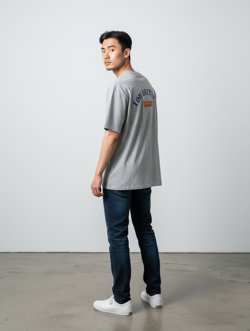 mi-DONE grey oversized cotton t-shirt with Low Battery graphic on back worn by a man with dark jeans and white sneakers