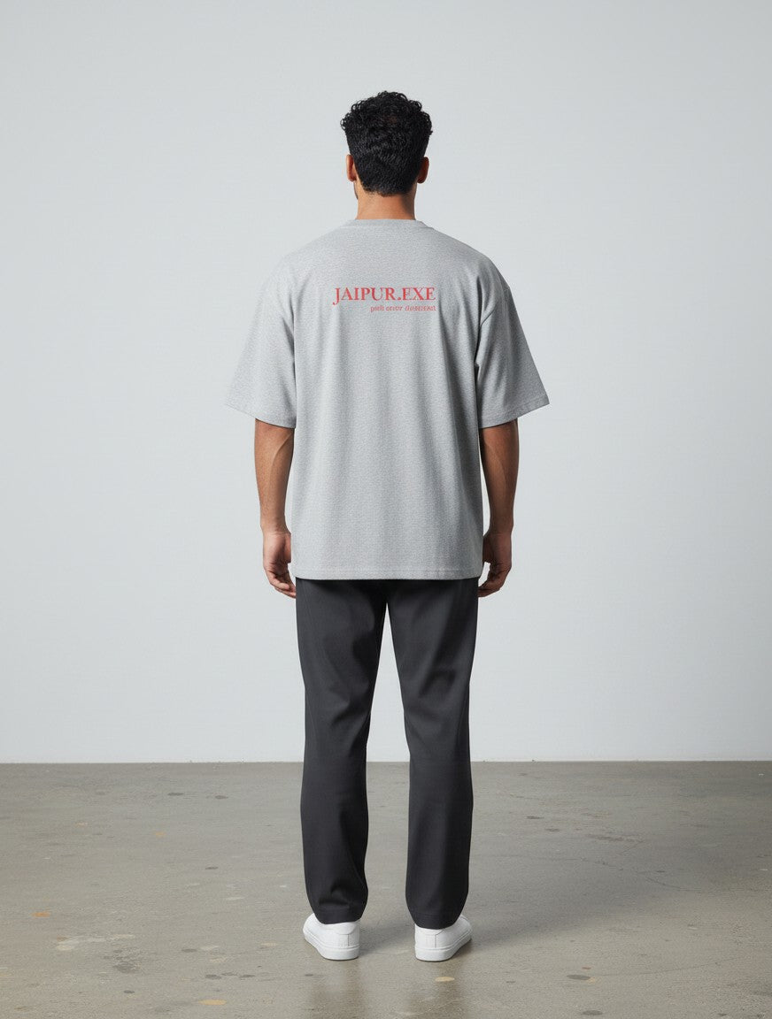 mi-DONE grey oversized cotton t-shirt with Jaipur.exe red graphic print on back, worn by a man with dark trousers.