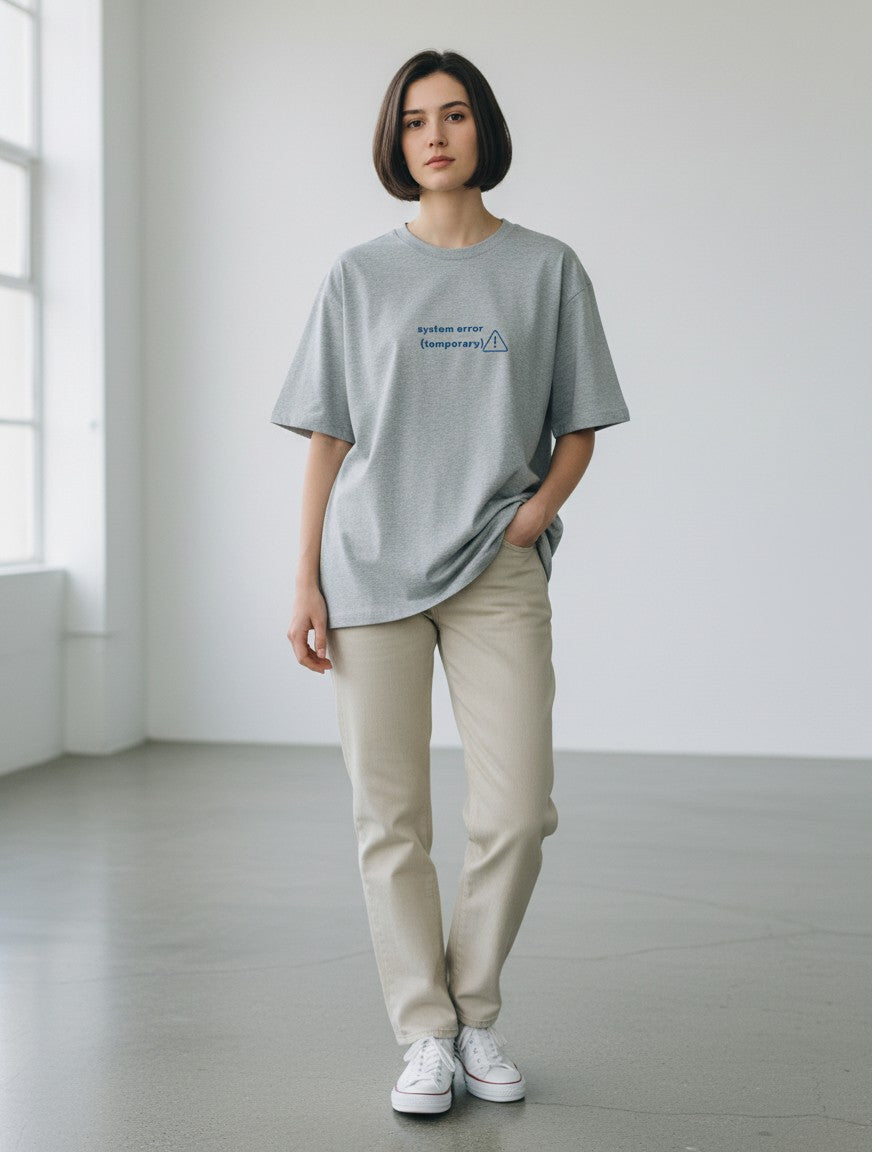 A model wearing a mi-DONE grey oversized cotton t-shirt with a System Error graphic print, paired with beige jeans.