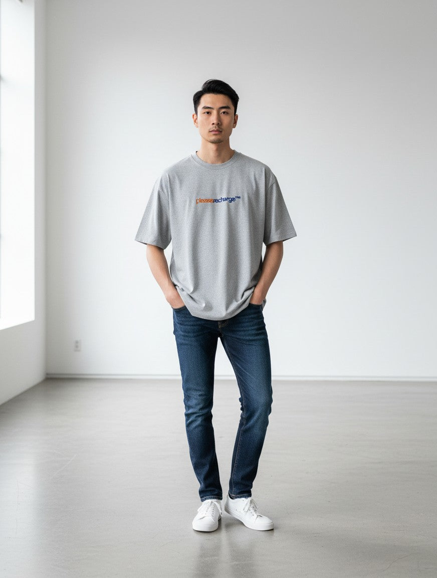 A man wearing a grey mi-DONE oversized cotton t-shirt with a Low Battery graphic print, paired with blue jeans.