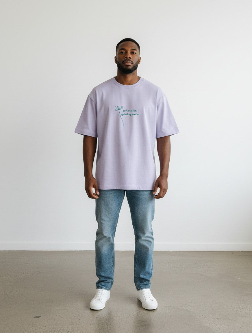 Model wearing a mi-DONE lavender oversized cotton t-shirt with a small graphic print on the chest and blue jeans.