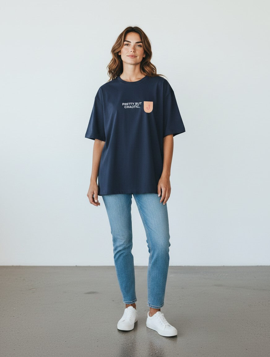 A woman wearing a navy blue mi-DONE oversized cotton t-shirt with a graphic print, paired with blue jeans and white sneakers.