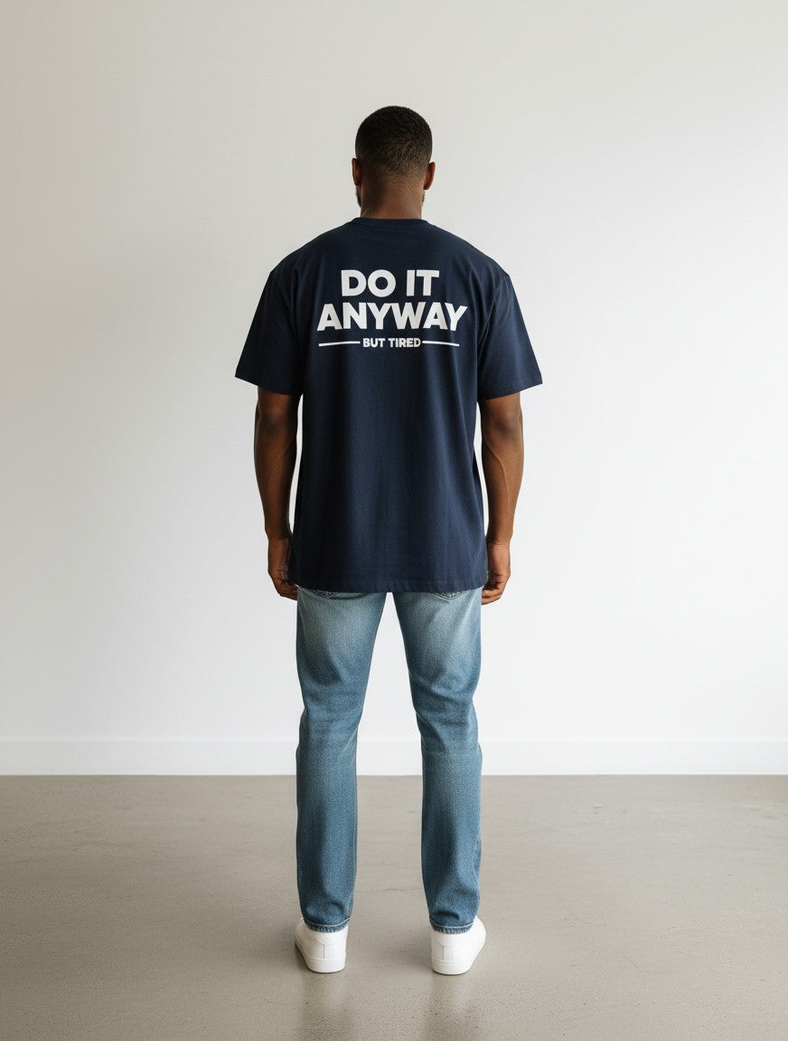 mi-DONE navy oversized cotton t-shirt with white Do It Anyway But Tired text on the back, worn by a man with jeans.