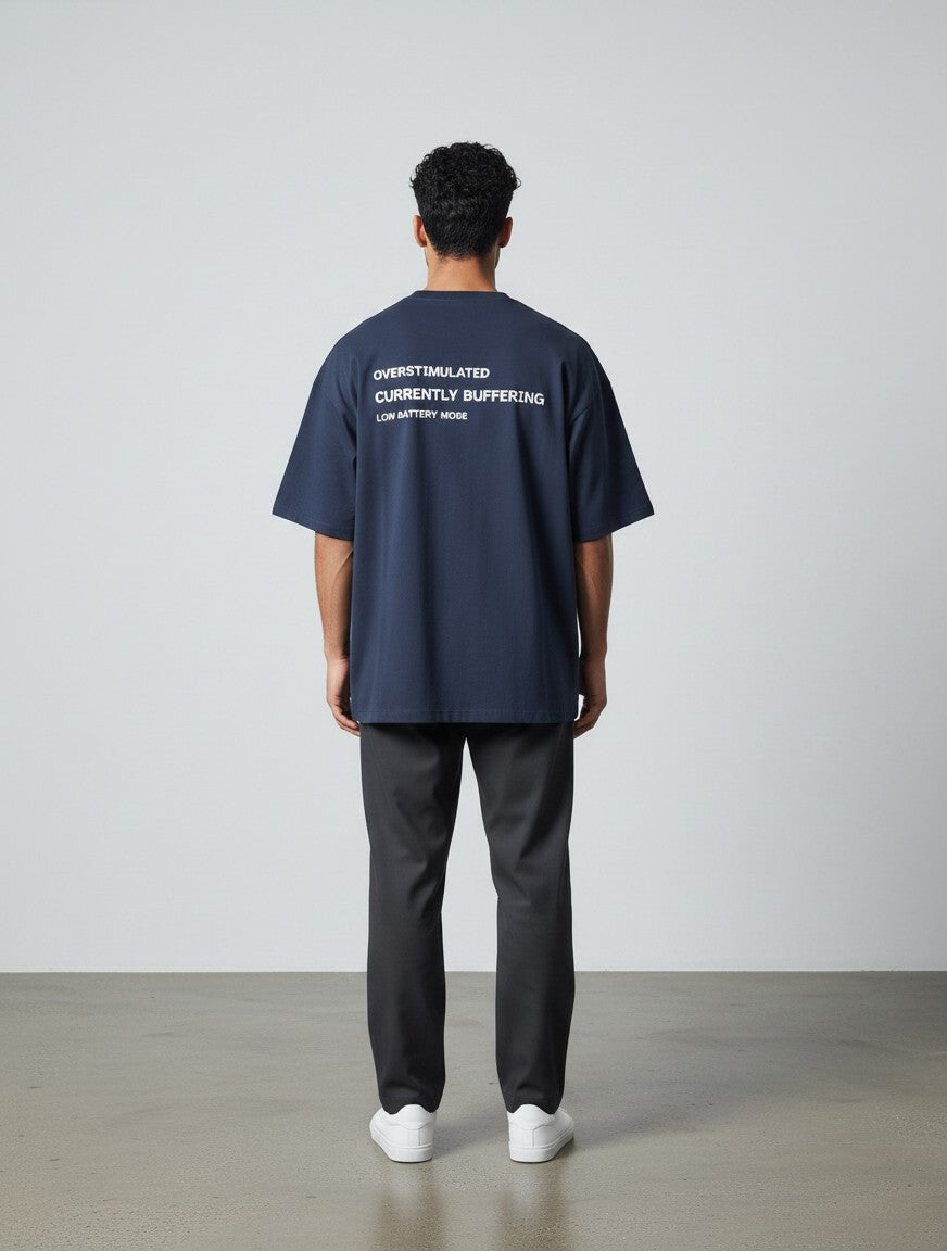 mi-DONE navy blue oversized cotton t-shirt with Overstimulated text print on the back, worn by a man from behind.