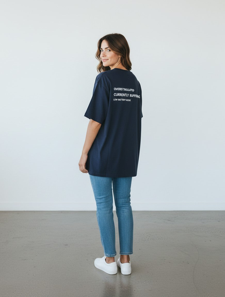 Woman wearing a navy blue mi-DONE oversized cotton t-shirt with Overstimulated text print on the back
