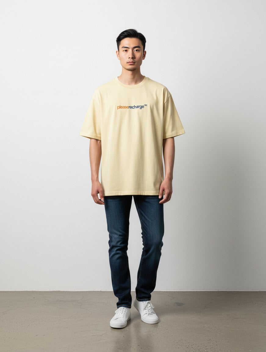 mi-DONE oversized beige cotton t-shirt with Low Battery graphic print, worn by a man with dark jeans and white sneakers