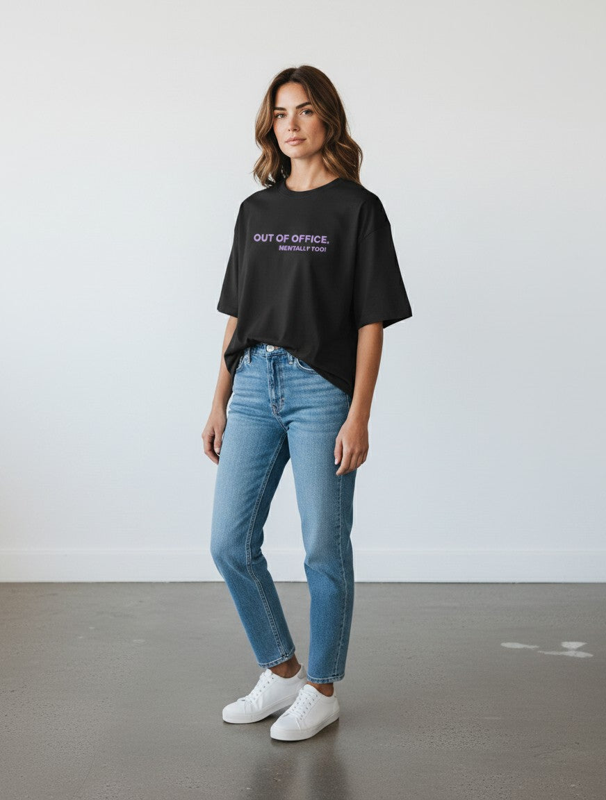 mi-DONE oversized black cotton t-shirt with Out Of Office print worn by a woman with blue jeans and white sneakers