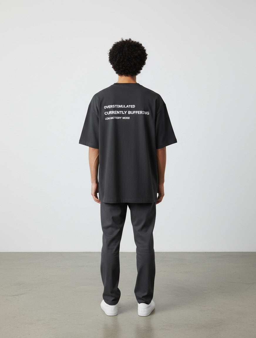 mi-DONE oversized charcoal grey cotton t-shirt with Overstimulated text print on the back, worn by a man