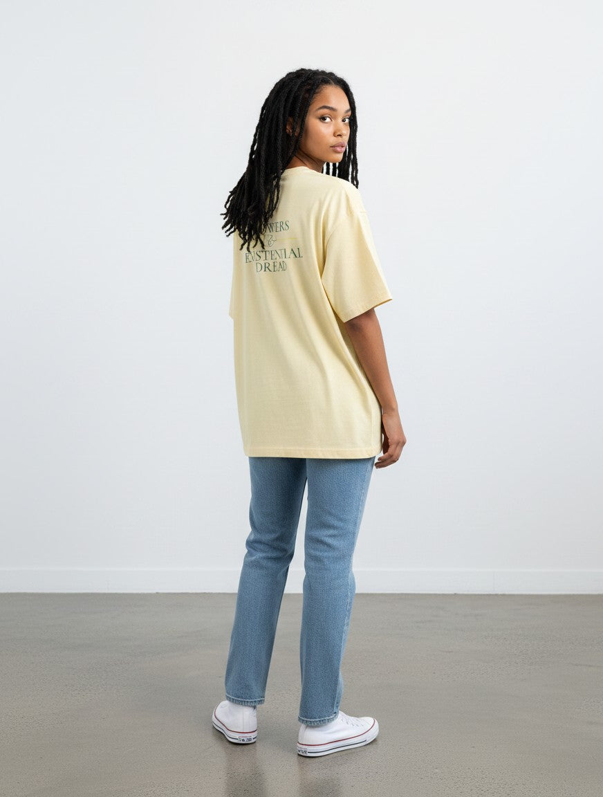 Model wearing a mi-DONE oversized cream cotton t-shirt with back graphic print, paired with blue jeans and white sneakers