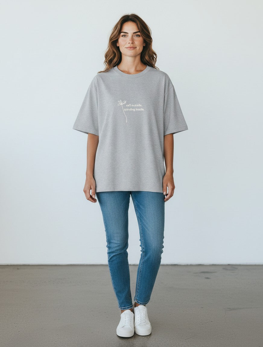 mi-DONE oversized grey cotton t-shirt with a small flower graphic and text on a woman wearing blue jeans