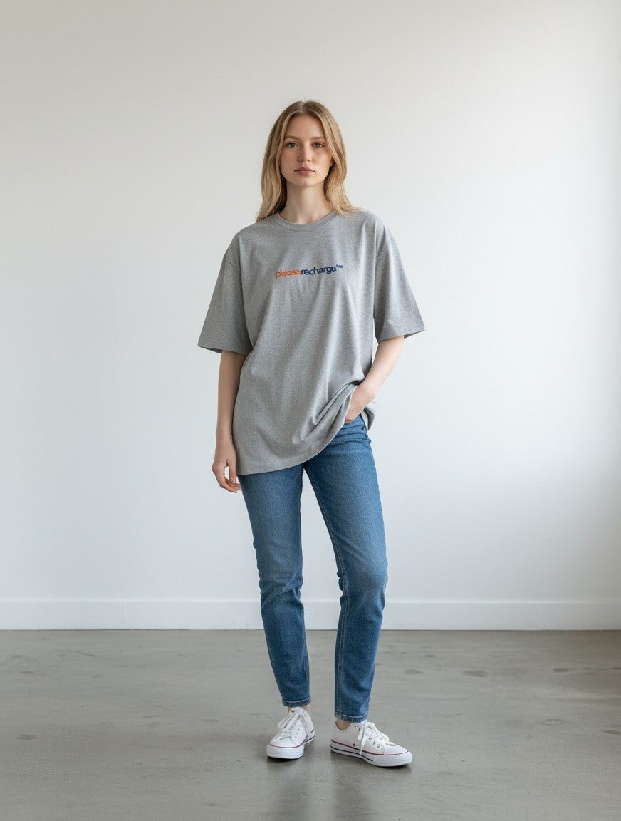 mi-DONE oversized grey cotton t-shirt with Please Recharge graphic, worn by a woman with blue jeans and white sneakers