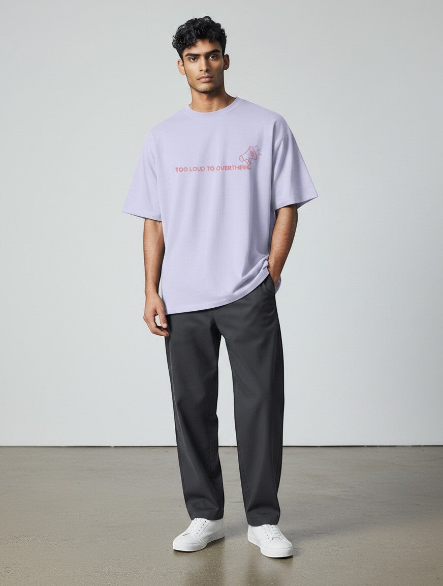 A male model wearing a mi-DONE oversized lavender round neck cotton t-shirt with a graphic print and dark trousers.