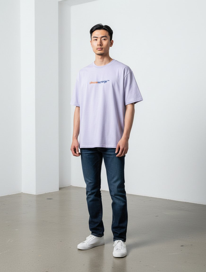 A man wearing a mi-DONE oversized lavender cotton t-shirt with a round neck and drop shoulders, paired with dark jeans.
