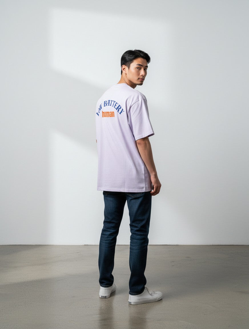 mi-DONE oversized lavender t-shirt with Low Battery graphic on back, worn by a man with dark jeans and white sneakers