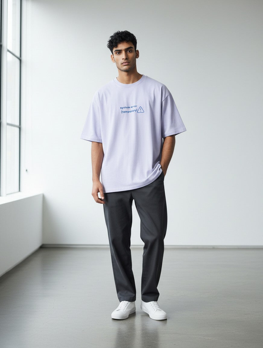 A man wearing a mi-DONE oversized lilac cotton t-shirt with a System Error graphic, paired with dark grey trousers.