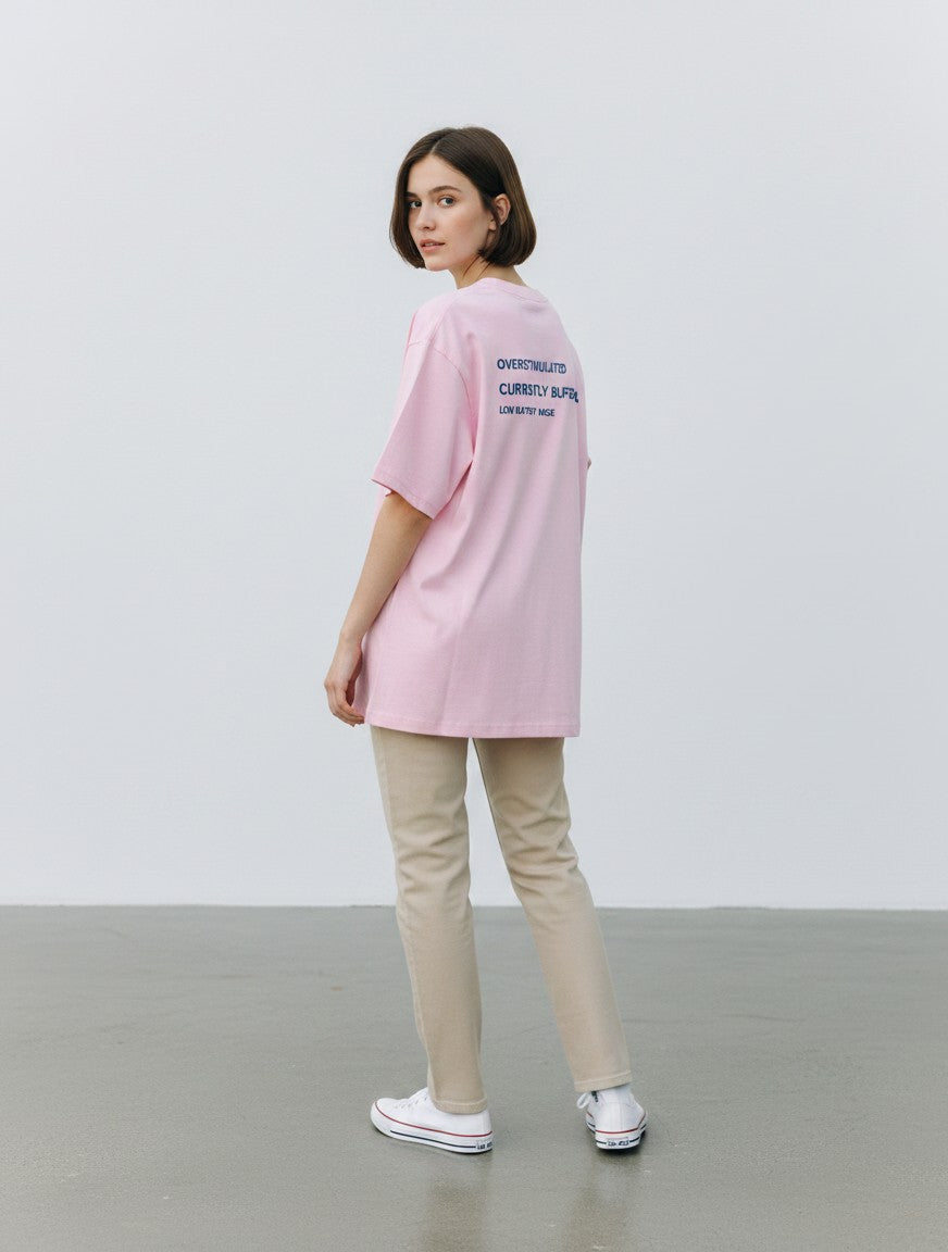 mi-DONE oversized pink cotton t-shirt with graphic print on back, worn by a woman with beige trousers and sneakers
