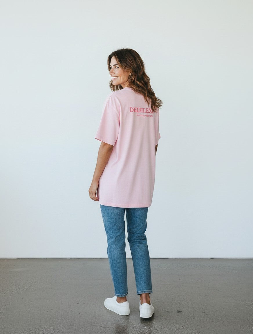 A woman wearing a mi-DONE oversized pink cotton T-shirt with Delhi graphic print on the back, paired with blue jeans.