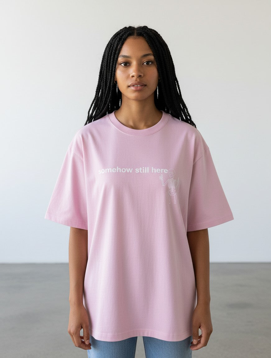 mi-DONE oversized pink cotton t-shirt with a skeleton graphic and somehow still here text on a model
