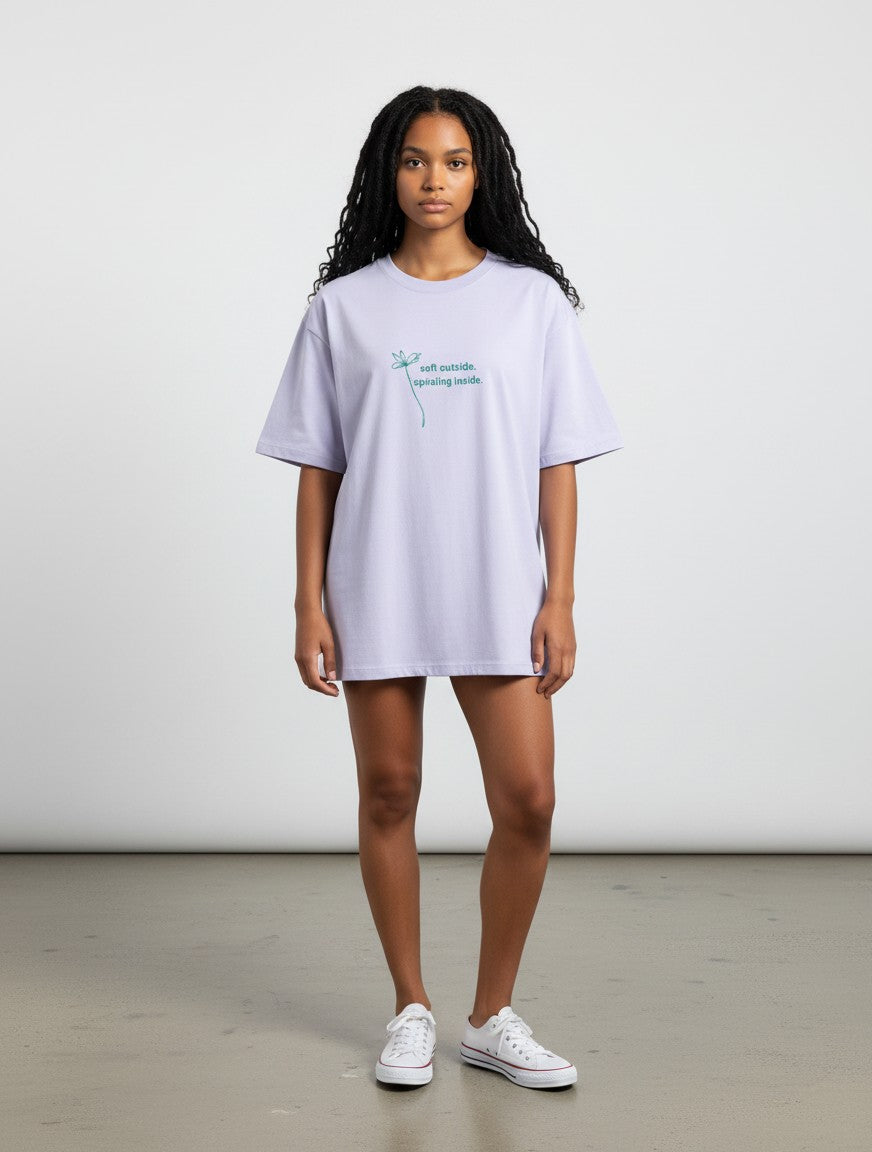 A model wearing a mi-DONE oversized light purple cotton t-shirt with a small floral graphic and text on the chest.