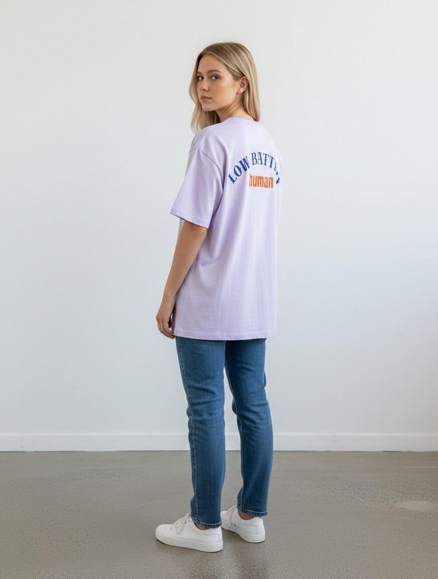 mi-DONE oversized light purple cotton t-shirt with Low Battery graphic on back, worn by a woman with blue jeans