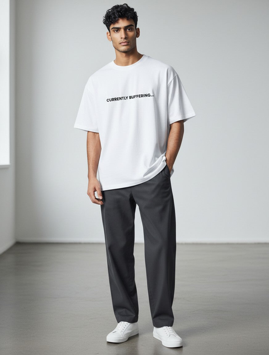 A male model wearing a white mi-DONE oversized cotton t-shirt with the text CURRENTLY BUFFERING printed on the chest.