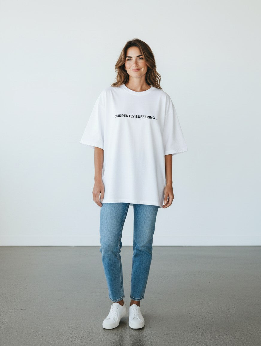 A woman wearing a white mi-DONE oversized cotton t-shirt with the text CURRENTLY BUFFERING printed on the chest.