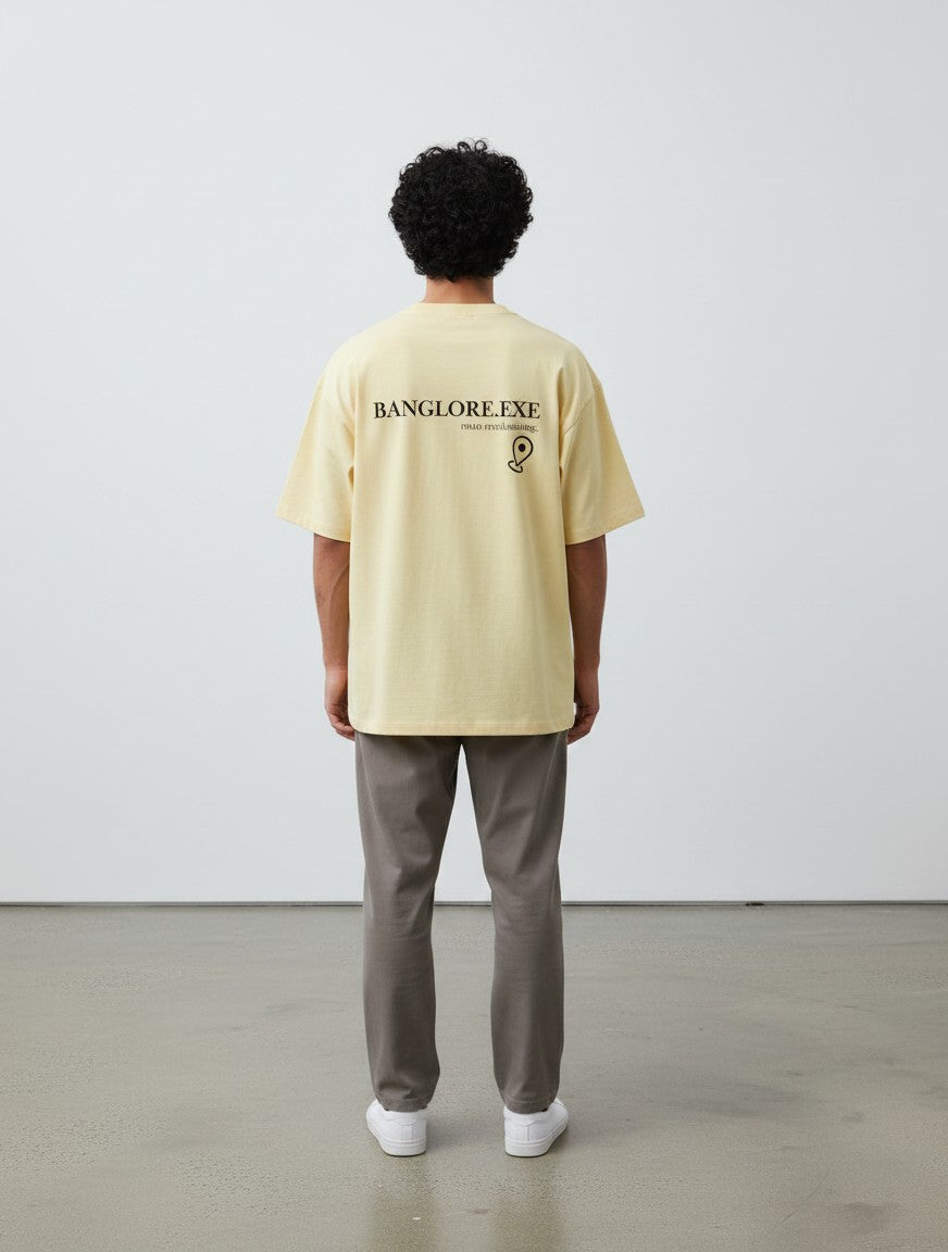mi-DONE oversized yellow cotton t-shirt with Bengaluru graphic print on back, worn by a man with grey trousers