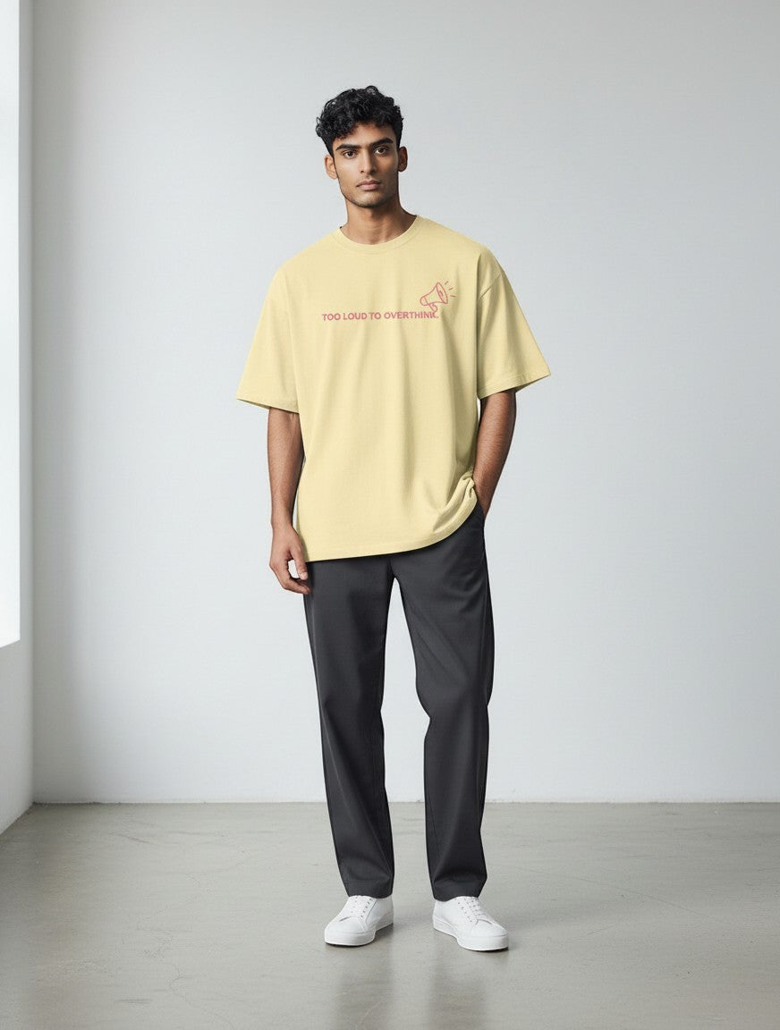 A man wearing a mi-DONE oversized pale yellow cotton t-shirt with a red graphic print and drop shoulders.