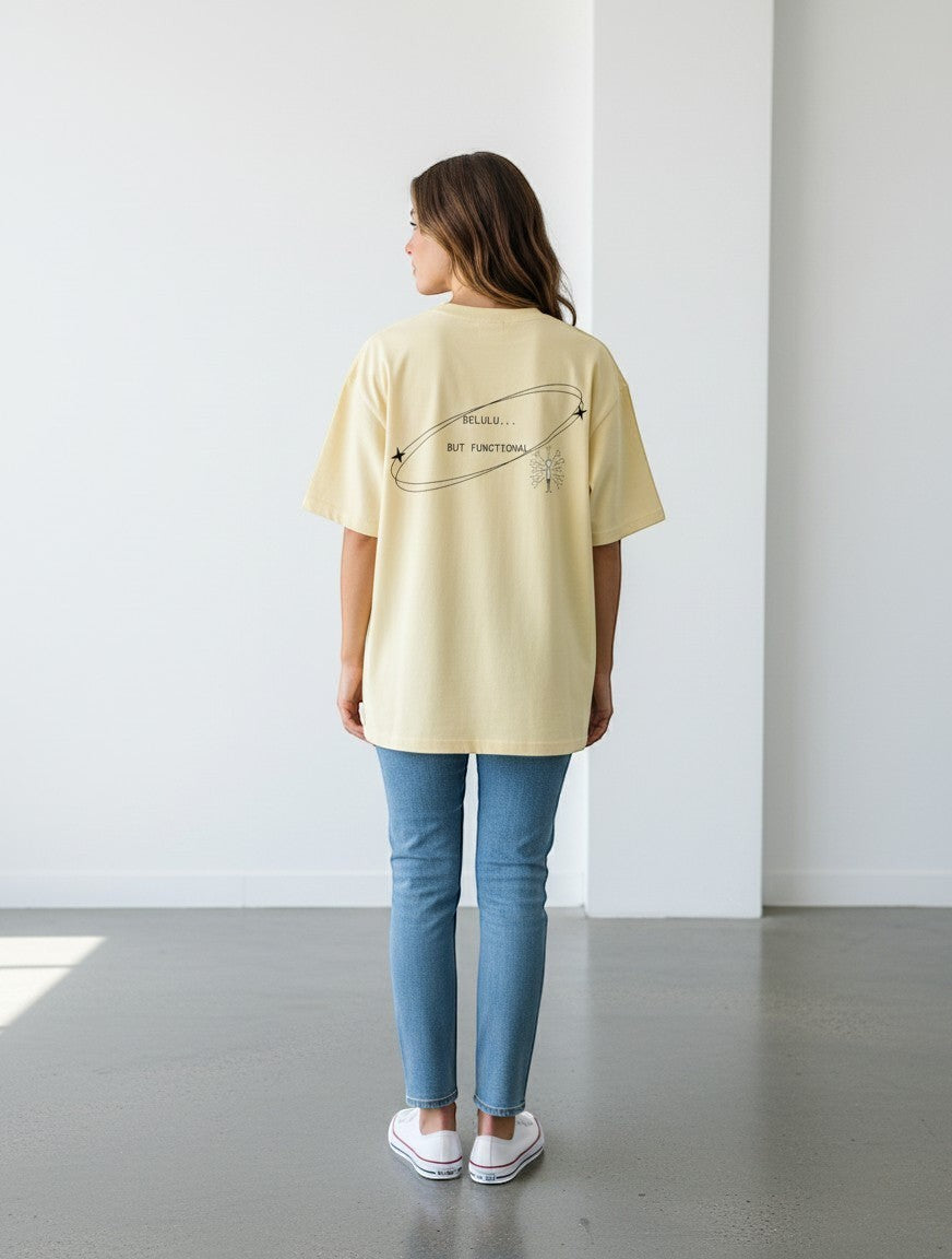 mi-DONE oversized pale yellow cotton t-shirt with Delulu But Functional graphic print on the back, worn with jeans