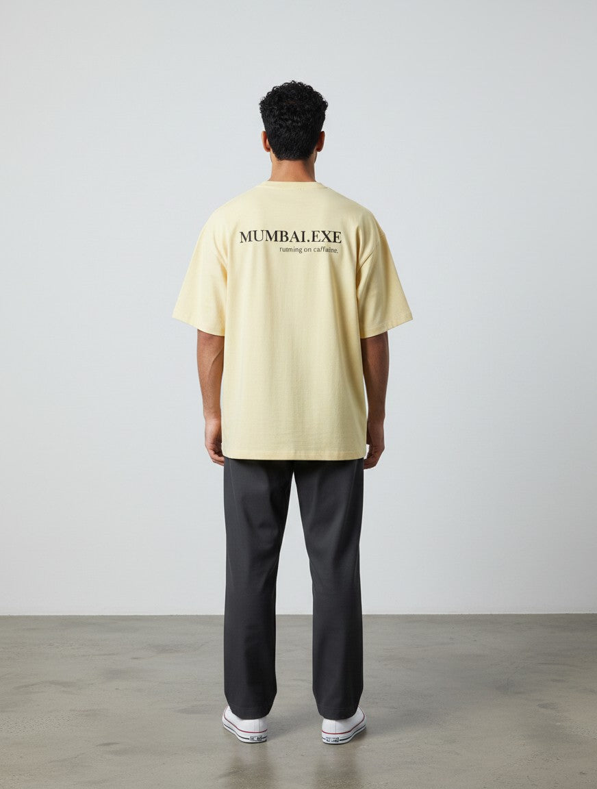 mi-DONE oversized yellow cotton t-shirt with Mumbai.exe graphic print on the back, worn by a man with dark trousers.