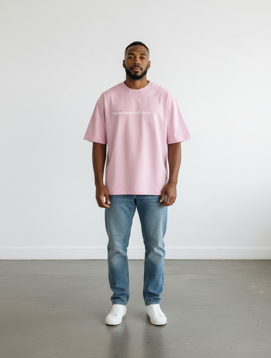 A model wearing a mi-DONE pink oversized cotton t-shirt with drop shoulders and a graphic print, paired with jeans.