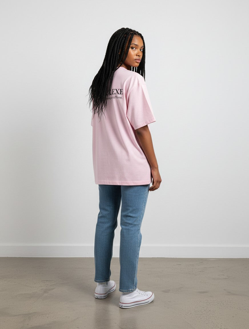 Model wearing a pink mi-DONE oversized cotton t-shirt with drop shoulders and black text print, paired with blue jeans