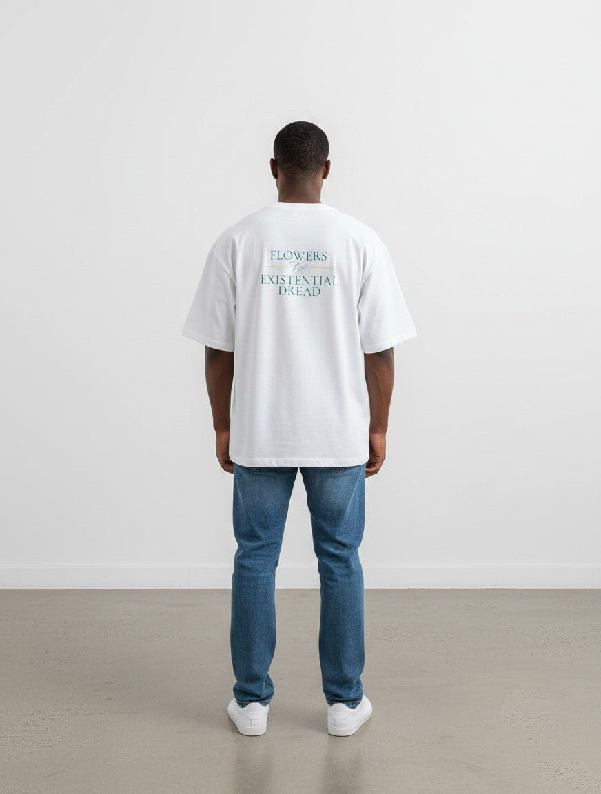 A man wearing a white mi-DONE oversized cotton t-shirt with a graphic print on the back, paired with blue jeans.
