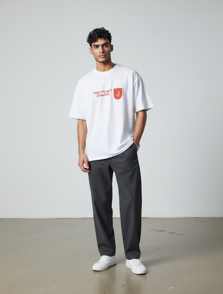 A man wearing a white mi-DONE oversized cotton t-shirt with Pretty But Chaotic text and a red J logo on the chest.