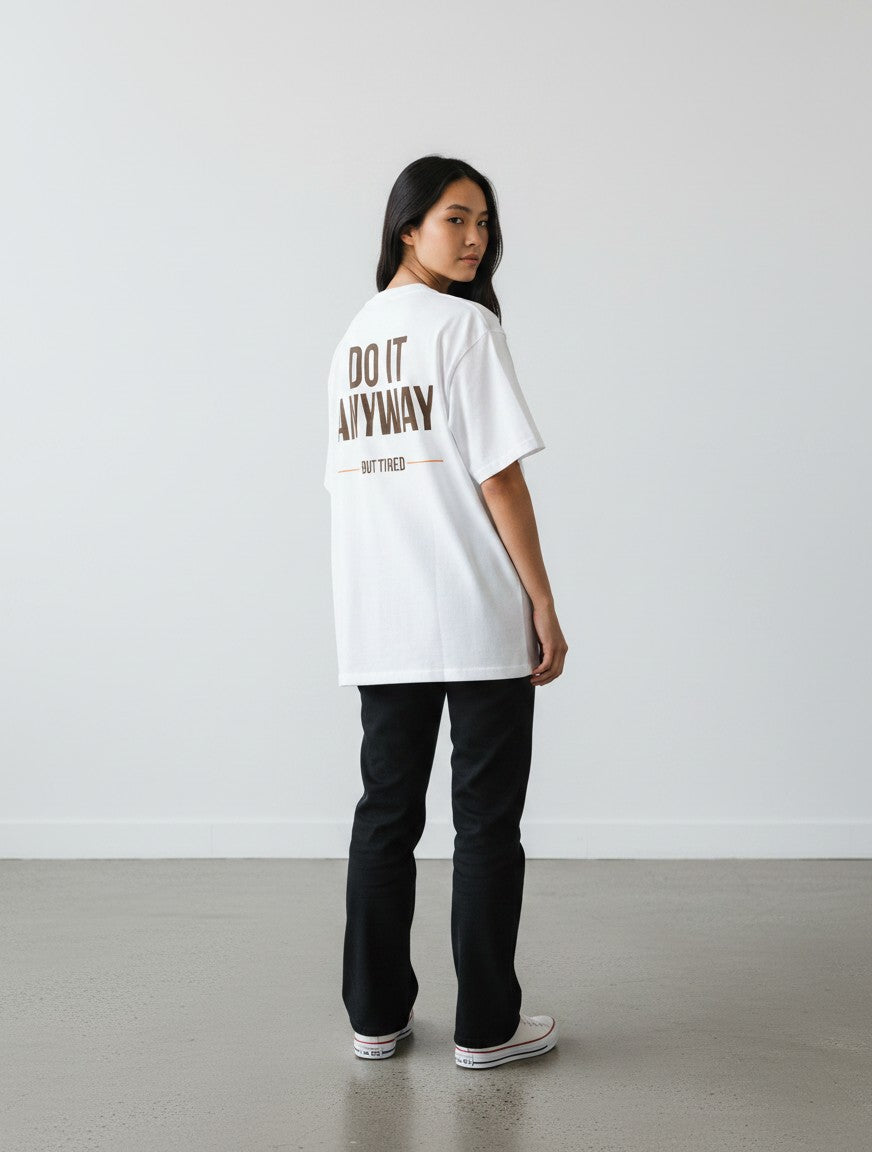 mi-DONE white oversized unisex cotton t-shirt with brown text print on back worn by a woman with black trousers