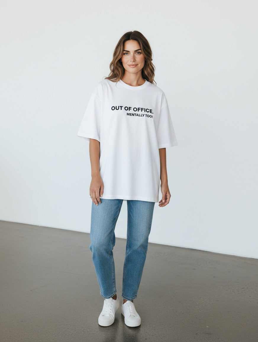 mi-DONE white oversized cotton t-shirt with Out of Office print worn by a woman with blue jeans and white sneakers