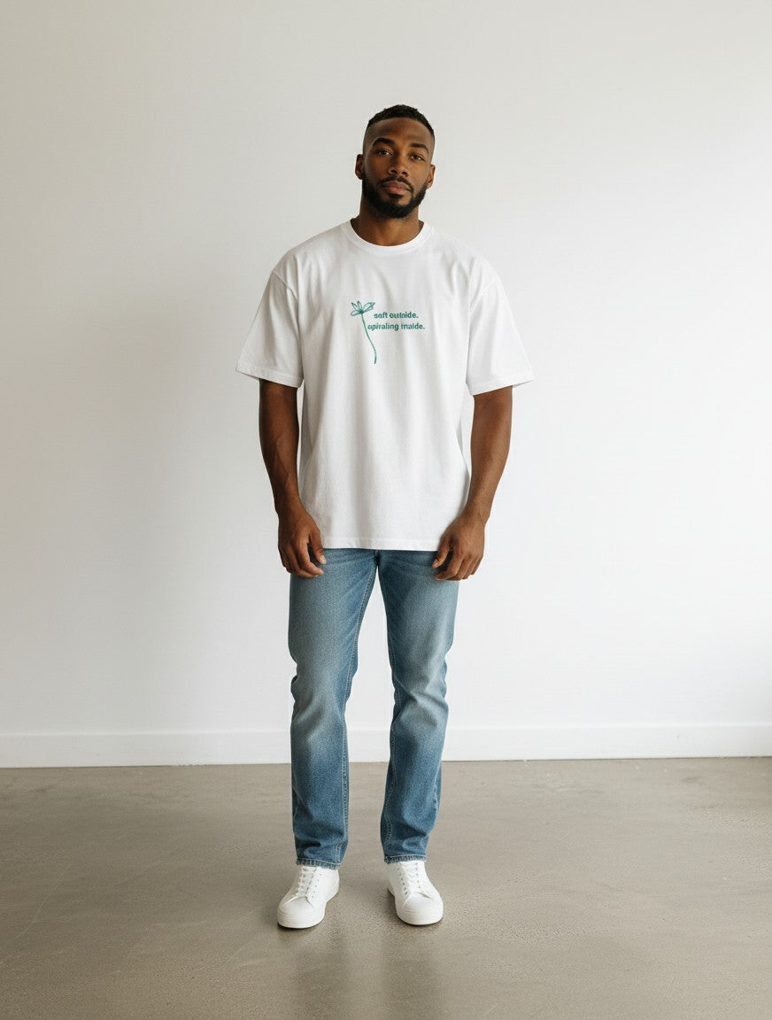 Model wearing a white mi-DONE oversized cotton t-shirt with a small green floral graphic and text on the chest.