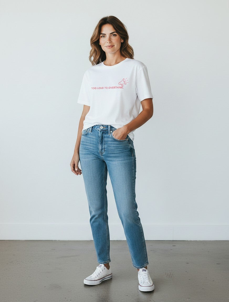 Woman wearing a white mi-DONE oversized cotton t-shirt with a pink graphic print, paired with blue jeans and sneakers.