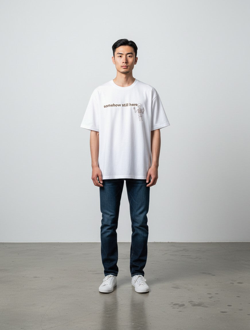 mi-DONE white oversized cotton t-shirt with skeleton graphic and somehow still here text on a male model